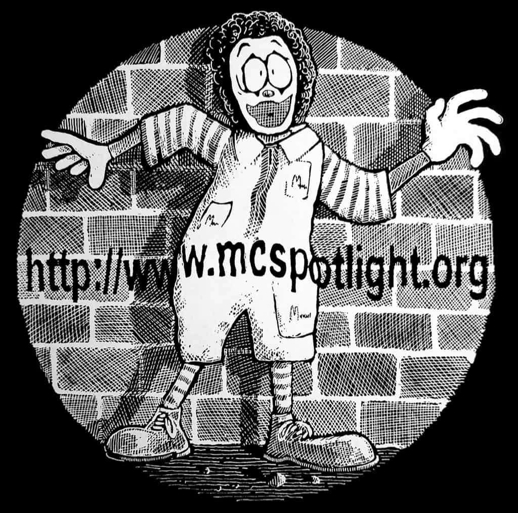 White-on-black cartoon of Ronald McDonald caught ina spotlight before a brick wall, with mcspotlight.org projected onto him